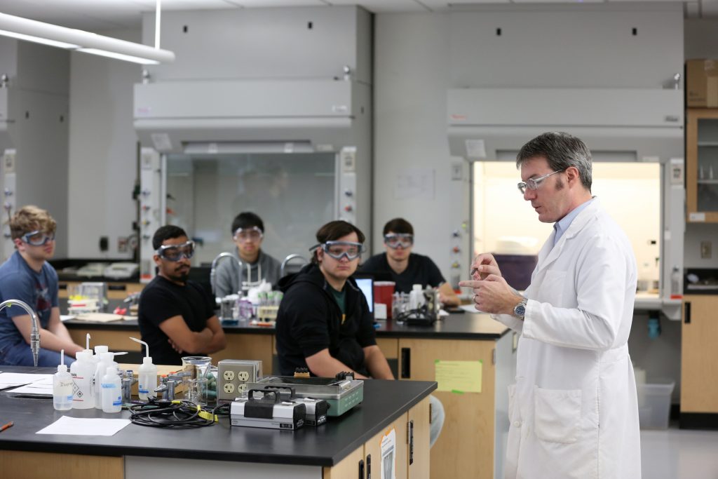 Students work in the lab during Associate Professor Matthew Ray's Chemistry of Materials class An engineering student works on mathematics coursework in Jarvis Hall Thursday, September 28, 2017. Pictured is the class comparing amorphous glass behavior with the crystalline solid behavior observed in the first part of the lab. They prepared batches of soda lime glass and varied the ingredients to change the melt viscosity and color. Glasses of various colors were prepared by adding small amounts of metal oxides to the glass mixture before firing to melt and react all of the ingredients together. The glass mixtures were placed into crucibles and heated overnight to 1150°C (2100°F), then poured onto an iron slab and allowed to cool. To observe fluorescence, the europium and terbium doped samples were illuminated with an ultraviolet lamp (365 nm light) which revealed the bright red and green fluorescence. (UW-Stout Photo by Brett T. Roseman)