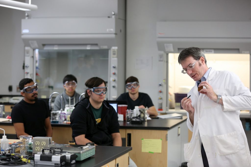 Students work in the lab during Associate Professor Matthew Ray's Chemistry of Materials class An engineering student works on mathematics coursework in Jarvis Hall Thursday, September 28, 2017. Pictured is the class comparing amorphous glass behavior with the crystalline solid behavior observed in the first part of the lab. They prepared batches of soda lime glass and varied the ingredients to change the melt viscosity and color. Glasses of various colors were prepared by adding small amounts of metal oxides to the glass mixture before firing to melt and react all of the ingredients together. The glass mixtures were placed into crucibles and heated overnight to 1150°C (2100°F), then poured onto an iron slab and allowed to cool. To observe fluorescence, the europium and terbium doped samples were illuminated with an ultraviolet lamp (365 nm light) which revealed the bright red and green fluorescence. (UW-Stout Photo by Brett T. Roseman)