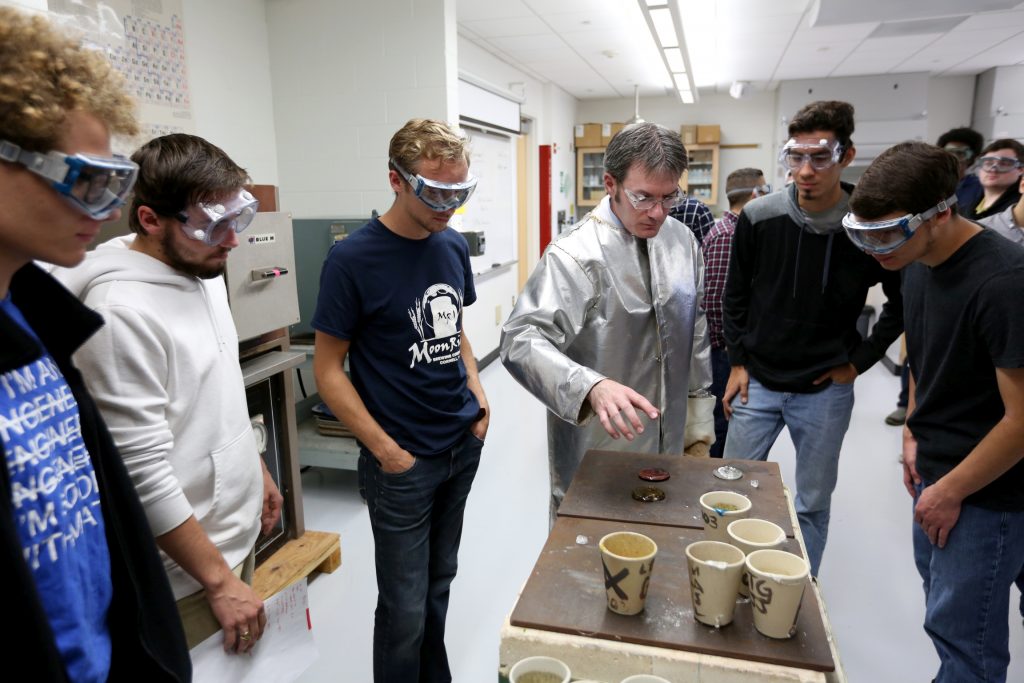 Students work in the lab during Associate Professor Matthew Ray's Chemistry of Materials class An engineering student works on mathematics coursework in Jarvis Hall Thursday, September 28, 2017. Pictured is the class comparing amorphous glass behavior with the crystalline solid behavior observed in the first part of the lab. They prepared batches of soda lime glass and varied the ingredients to change the melt viscosity and color. Glasses of various colors were prepared by adding small amounts of metal oxides to the glass mixture before firing to melt and react all of the ingredients together. The glass mixtures were placed into crucibles and heated overnight to 1150°C (2100°F), then poured onto an iron slab and allowed to cool. To observe fluorescence, the europium and terbium doped samples were illuminated with an ultraviolet lamp (365 nm light) which revealed the bright red and green fluorescence. (UW-Stout Photo by Brett T. Roseman)