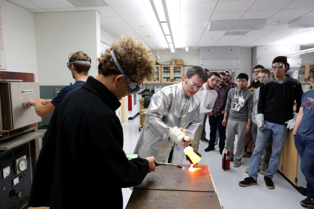 Students work in the lab during Associate Professor Matthew Ray's Chemistry of Materials class An engineering student works on mathematics coursework in Jarvis Hall Thursday, September 28, 2017. Pictured is the class comparing amorphous glass behavior with the crystalline solid behavior observed in the first part of the lab. They prepared batches of soda lime glass and varied the ingredients to change the melt viscosity and color. Glasses of various colors were prepared by adding small amounts of metal oxides to the glass mixture before firing to melt and react all of the ingredients together. The glass mixtures were placed into crucibles and heated overnight to 1150°C (2100°F), then poured onto an iron slab and allowed to cool. To observe fluorescence, the europium and terbium doped samples were illuminated with an ultraviolet lamp (365 nm light) which revealed the bright red and green fluorescence. (UW-Stout Photo by Brett T. Roseman)