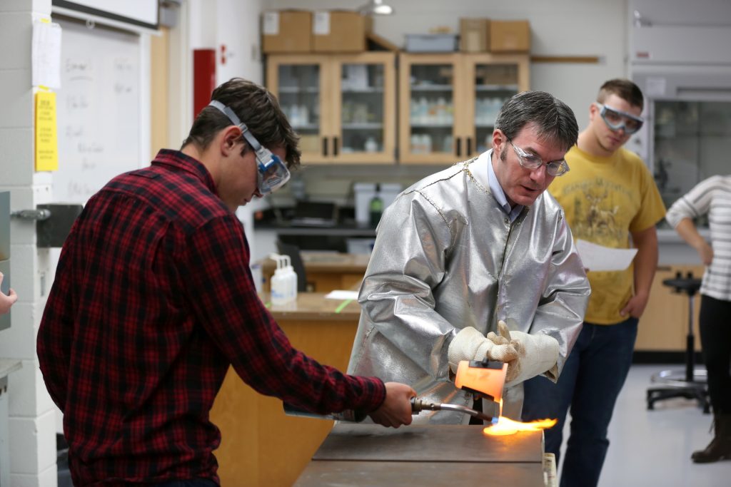 Students work in the lab during Associate Professor Matthew Ray's Chemistry of Materials class An engineering student works on mathematics coursework in Jarvis Hall Thursday, September 28, 2017. Pictured is the class comparing amorphous glass behavior with the crystalline solid behavior observed in the first part of the lab. They prepared batches of soda lime glass and varied the ingredients to change the melt viscosity and color. Glasses of various colors were prepared by adding small amounts of metal oxides to the glass mixture before firing to melt and react all of the ingredients together. The glass mixtures were placed into crucibles and heated overnight to 1150°C (2100°F), then poured onto an iron slab and allowed to cool. To observe fluorescence, the europium and terbium doped samples were illuminated with an ultraviolet lamp (365 nm light) which revealed the bright red and green fluorescence. (UW-Stout Photo by Brett T. Roseman)